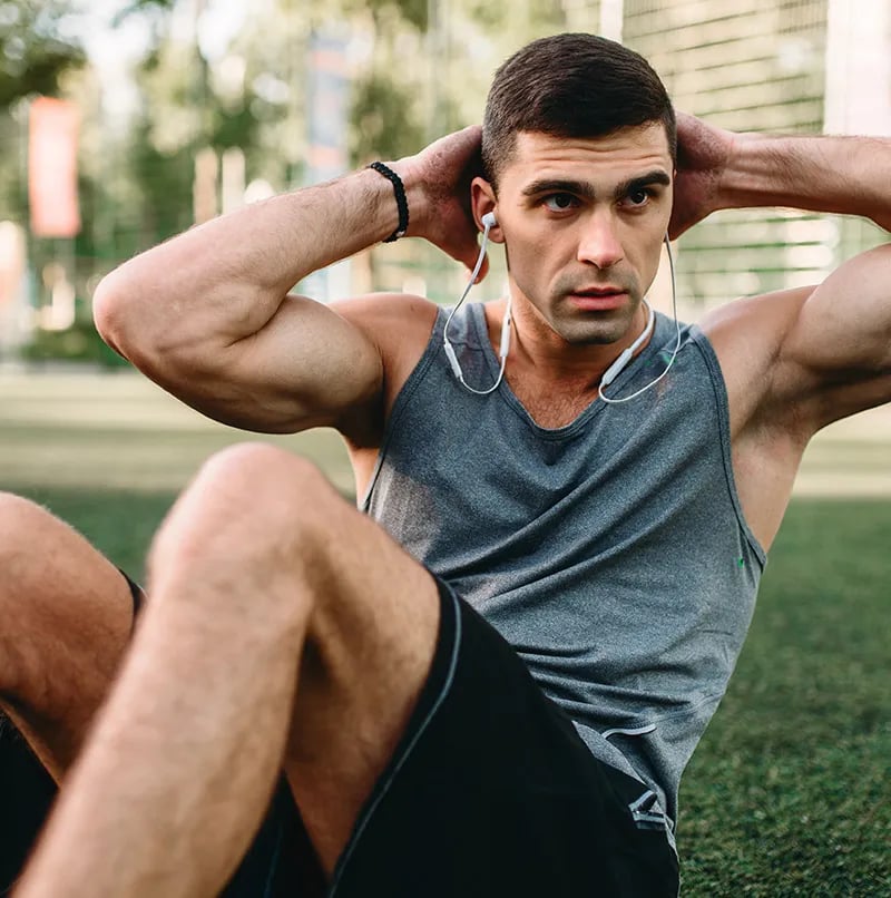 Male athlete doing sit-ups outside on the grass
