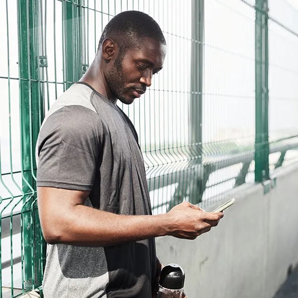 An athletic man who has stopped training to look at his phone